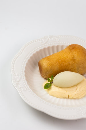 Elegant serving of Neapolitan rum baba dessert with creamy custard and refreshing sorbet on a white...