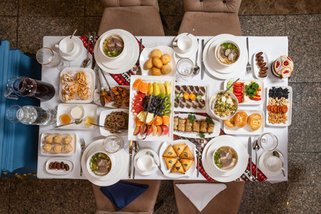 Top view of a lavish table with soups, fruits, sweets, and appetizers. Perfect for weddings,...
