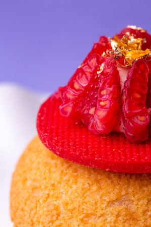 Macro of dessert with raspberry and gold - luxury, texture and bold colors on purple