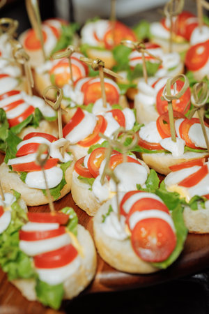 Close-up of mini canapes with mozzarella, tomato and basil on wooden boardの写真素材