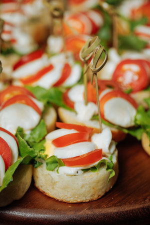 Close-up of mini caprese canapes with mozzarella, tomato and basil on wooden boardの写真素材