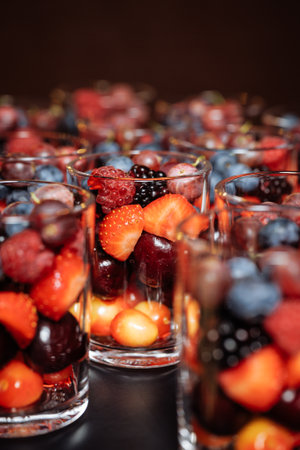 Individual servings of vibrant strawberries, blueberries, blackberries and cherries in transparent glasses. Ideal for luxury catering, wedding styling or health brand campaignsの写真素材