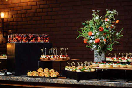 Elegant buffet table featuring mini sandwiches, pastries, canapes and fresh blooms.