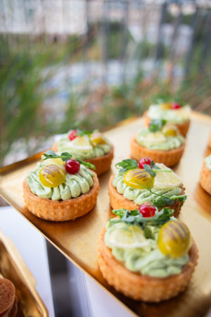 Delicate pastry shells topped with fresh herbs, pickles and berries - perfect for luxury catering, garden parties or gourmet food branding.の写真素材