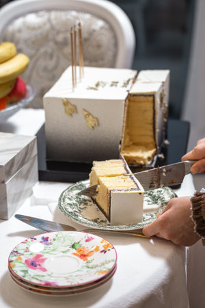 Hands slicing elegant white cake with gold rocket topper at celebratory eventの写真素材