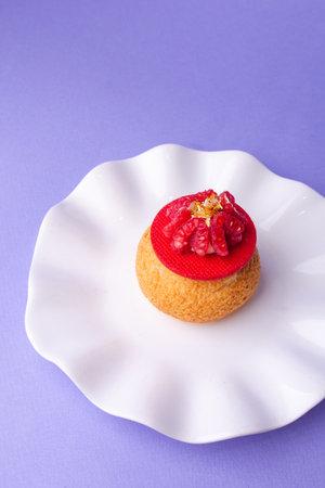 Top view of dessert with raspberry and gold on white plate, minimalist sweet aesthetic on purple background.の写真素材