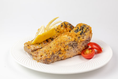 Close-up of baked fish in crispy crust with lemon and cherry tomatoes on white background - appetizing dishの写真素材