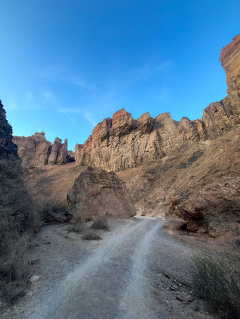 Inside the canyon: dusty road between rocky walls under clear blue sky.
