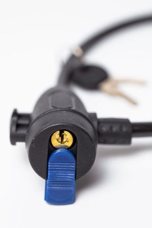 Close-up of black cable lock with blue release lever and keyhole on white background