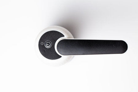 White automatic soap dispenser with black lever close-up on white background.