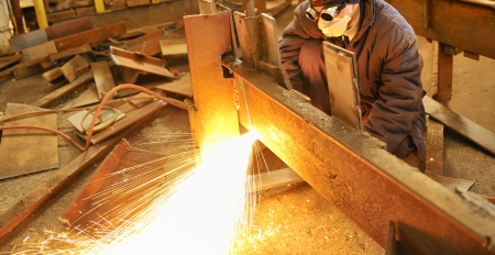 worker using torch cutter to cut through metal