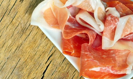Slices of prosciutto on old woodの写真素材