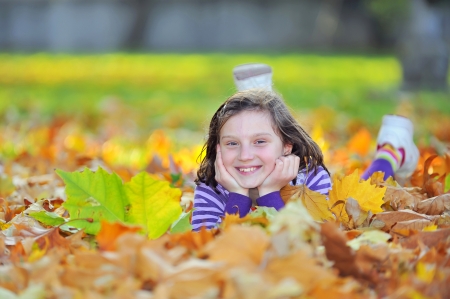 little girl laying on autumn leaves の写真素材
