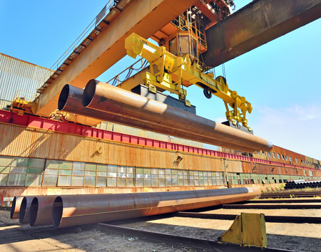 Loading pipes With Bridge Crane on industrial placeの写真素材