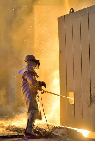 A steel worker takes a sample from ovenの写真素材