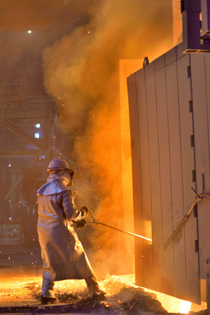 Worker in a foundry. Red color is a reflection of the molten metal.の写真素材