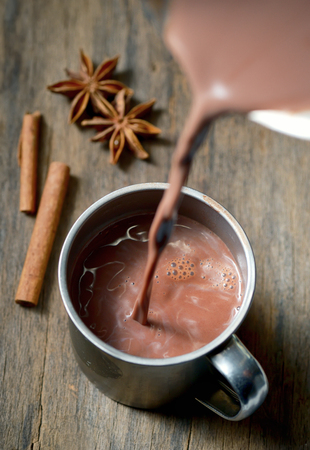 Hot chocolate with cinnamon stick on wooden tableの写真素材