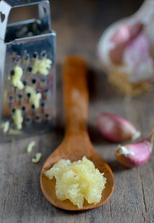 Garlic in spoon on wooden backgroundの写真素材