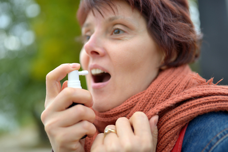 Young woman using throat spray in cold seasonの写真素材