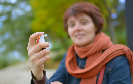Young woman using throat spray in cold seasonの写真素材