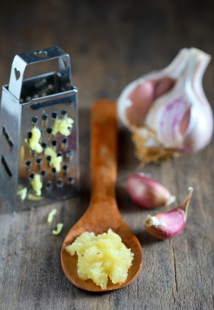 Garlic in spoon on wooden backgroundの写真素材