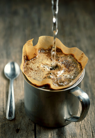 Ground coffee in filter holder isolated on wooden backgroundの写真素材