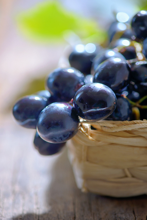 grapes in a basket on wooden backgroundの写真素材