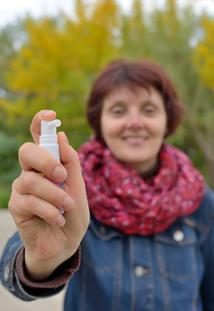Woman using throat spray in cold seasonの写真素材