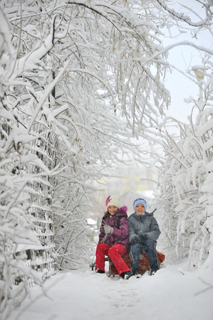 Two kids sliding with sledding in the snowの写真素材