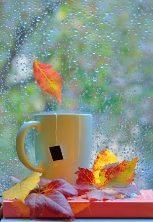 Tea cup at the window with  leaves and drops after rain in autumnの写真素材