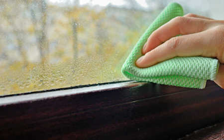Woman cleaning water  condensation on windowの写真素材