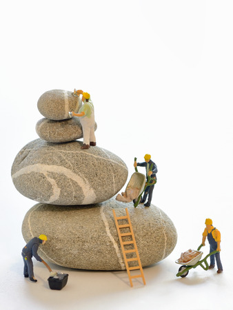 Pebbles stack and figurines of construction workersの写真素材