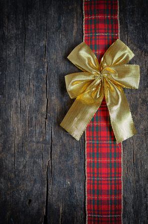 Christmas  ribbon and golden gift bow isolated on old wooden backgroundの写真素材