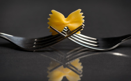 pasta farfalle on a fork on black backgroundの写真素材