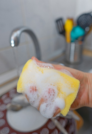Close up hands with gloves of woman washing dishesの写真素材
