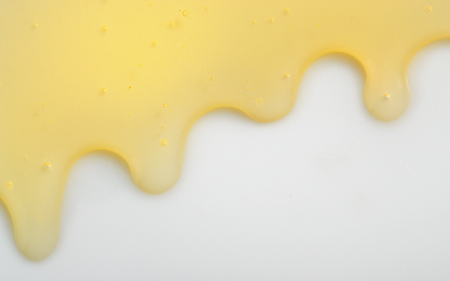 Honey liqiud flowing down on white backgroundの写真素材
