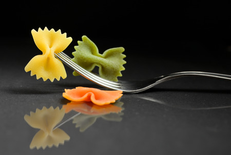 pasta farfalle on a fork on black backgroundの写真素材