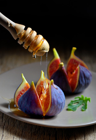 Honey dipper and figs on plateの写真素材