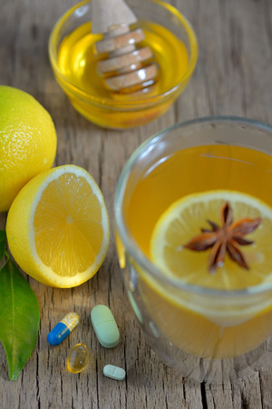 Hot lemon tea and pills on wooden tableの写真素材