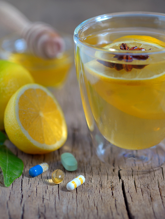 Hot lemon tea and pills on wooden tableの写真素材