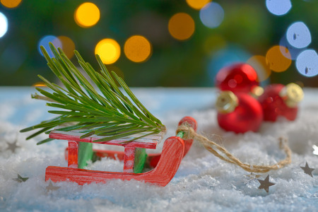 Red sleigh toy and Christmas tree on fake snowの写真素材