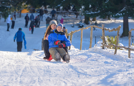 teenagers slide downhill in wintertimeの写真素材