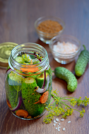 Pickled cucumbers, homemade preserved on wooden tableの写真素材