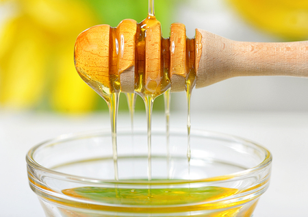 Golden honey dripping from dipperの写真素材
