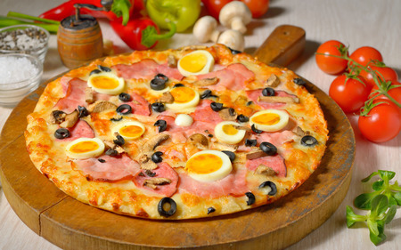 Pizza and ingredients on old wooden boardの写真素材