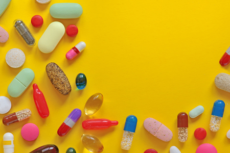 Many colorful pills isolated on yellow backgroundの写真素材