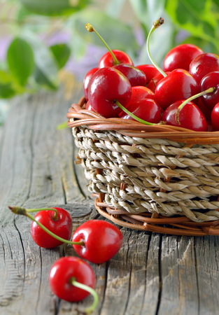 ripe cherries in a basket on wooden tableの写真素材