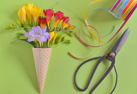 Freesias flowers in ice cream waffles and vintage scissorsの写真素材
