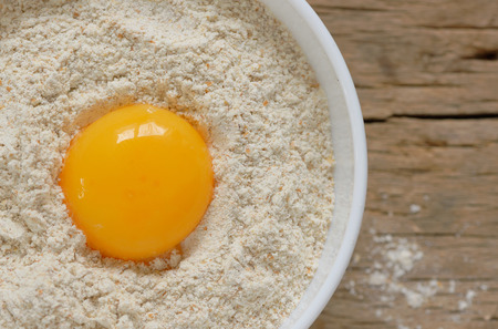 Flour and egg ready for mixing on wooden tableの写真素材
