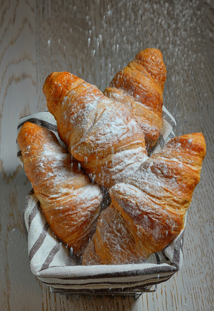 croissants in a basket on wooden tableの写真素材